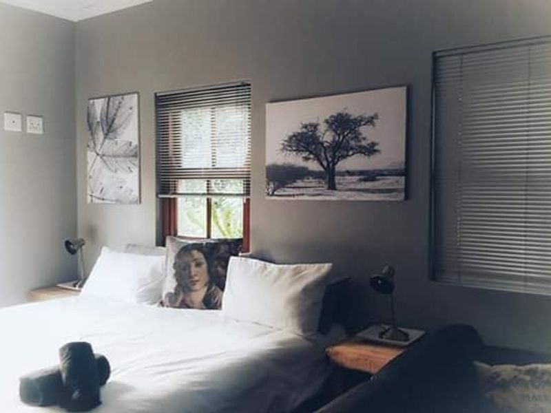 A cozy bedroom featuring neutral grey walls and functional venetian blinds, providing a comfortable and well-lit sleeping space.