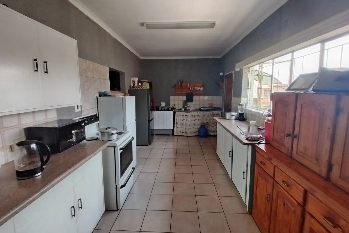 A functional galley-style kitchen featuring tiled flooring, laminate countertops, built-in cabinetry, and a freestanding stove, offering potential for modern updates.