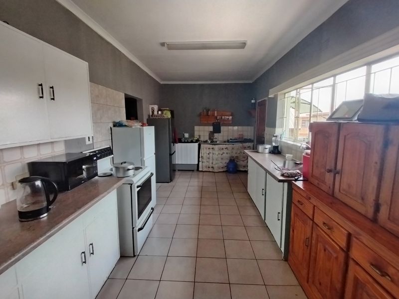 A functional galley-style kitchen featuring tiled flooring, laminate countertops, built-in cabinetry, and a freestanding stove, offering potential for modern updates.