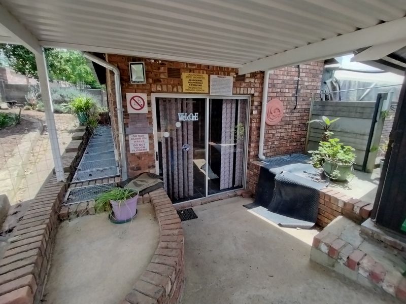 A covered patio area featuring a brick facade, concrete flooring, and a sliding glass door entrance.