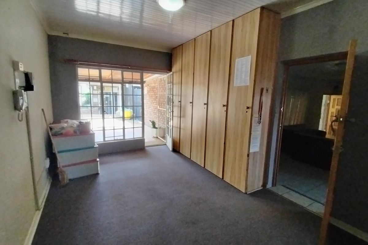 A spacious living area featuring extensive built-in storage cupboards, carpeted flooring, and direct access to an outdoor patio area through a glass door.