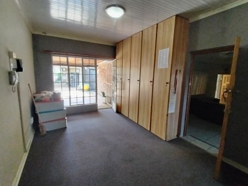 A spacious living area featuring extensive built-in storage cupboards, carpeted flooring, and direct access to an outdoor patio area through a glass door.