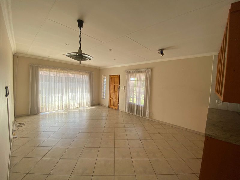Spacious open-plan living area featuring tiled flooring, natural light through sliding doors, and direct access to the entrance.