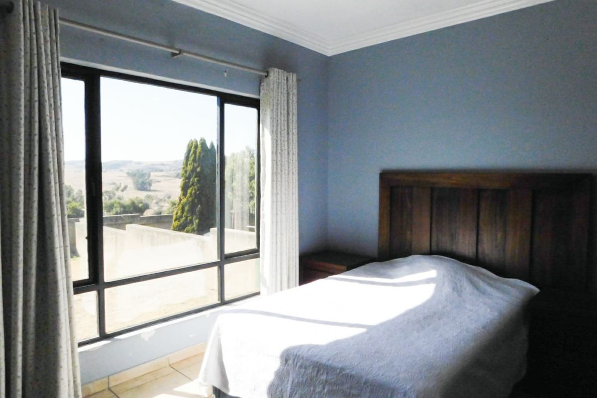 A bedroom featuring large windows with scenic views, tiled flooring, and crown molding.