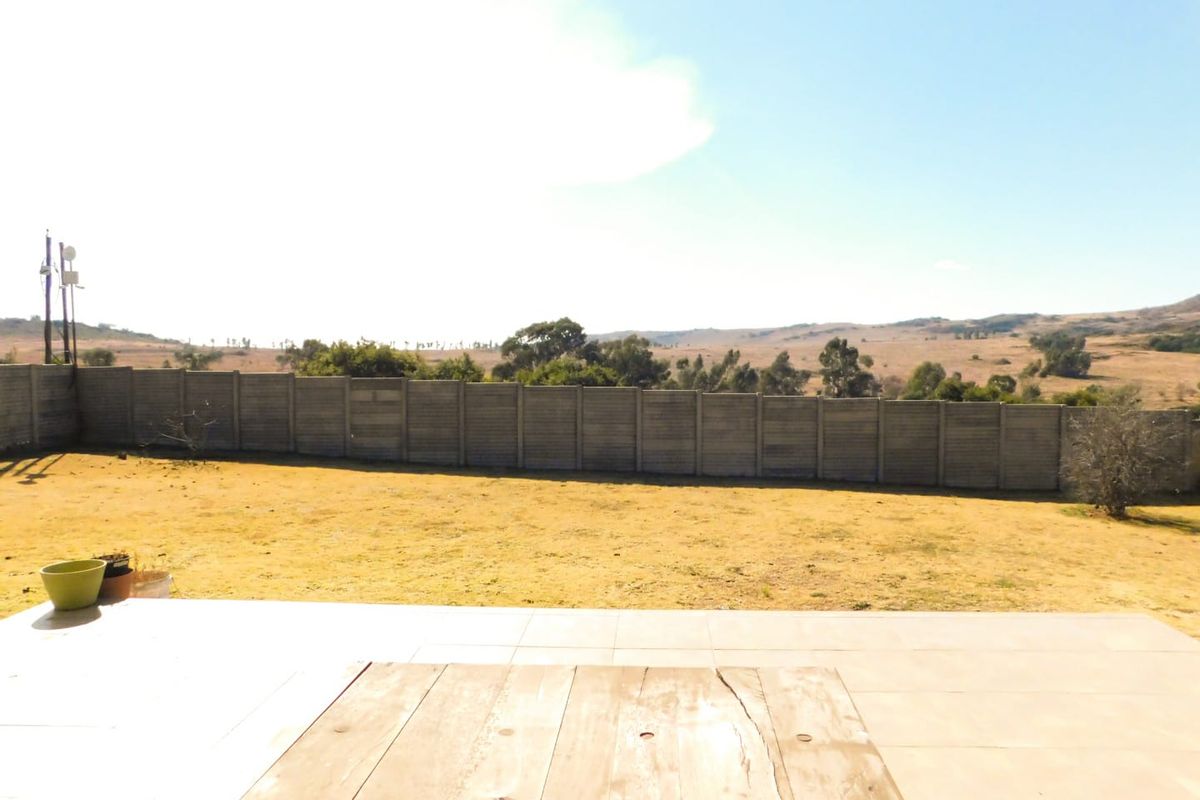 A spacious rear garden featuring a tiled patio area and a concrete boundary wall, offering expansive views of the surrounding landscape.