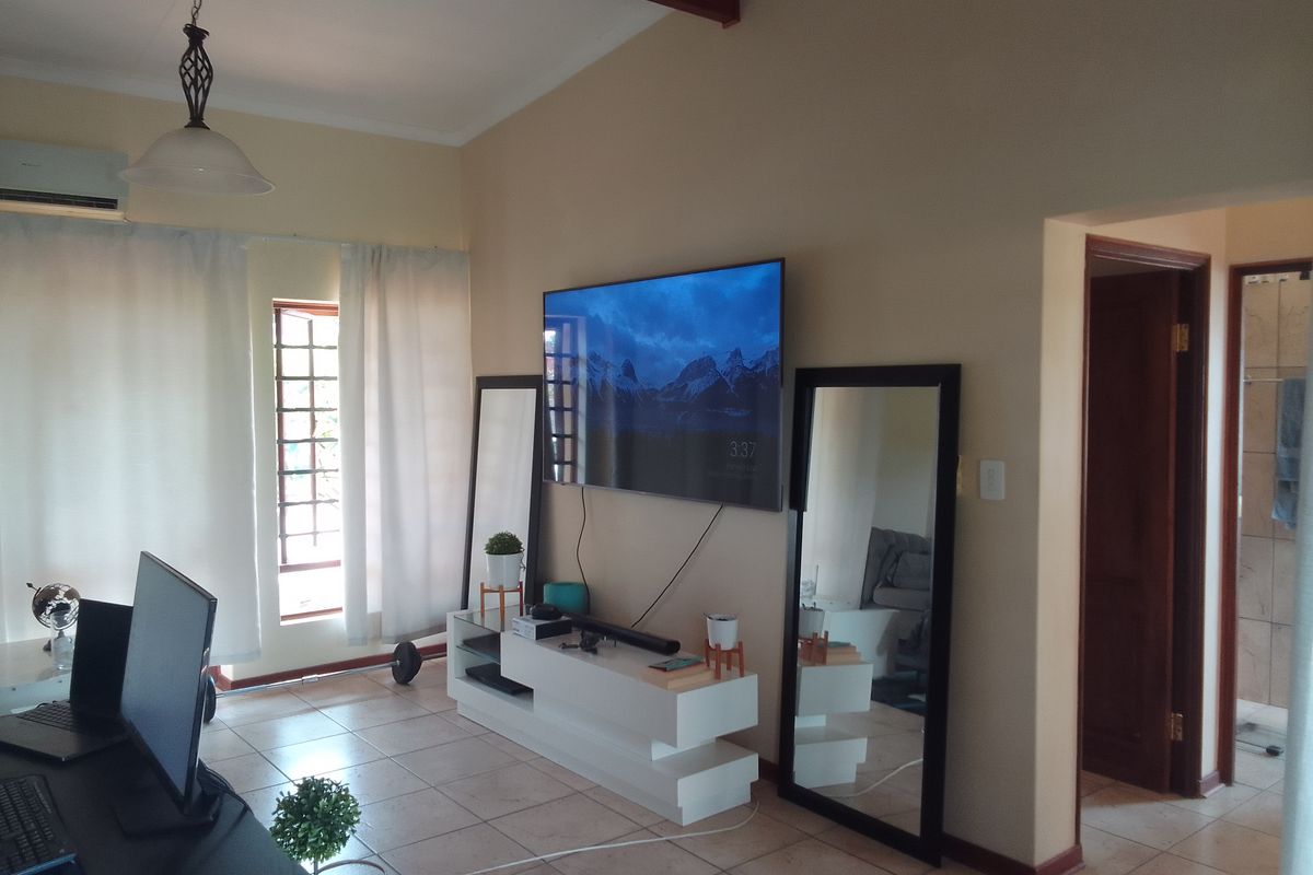 A living area featuring tiled flooring, a ceiling beam, and a doorway leading to an adjacent room.