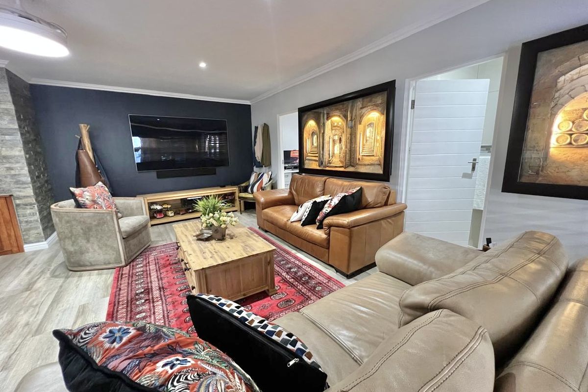A well-maintained living room featuring a stone accent wall, recessed downlighting, and modern laminate flooring, creating a comfortable and inviting atmosphere.