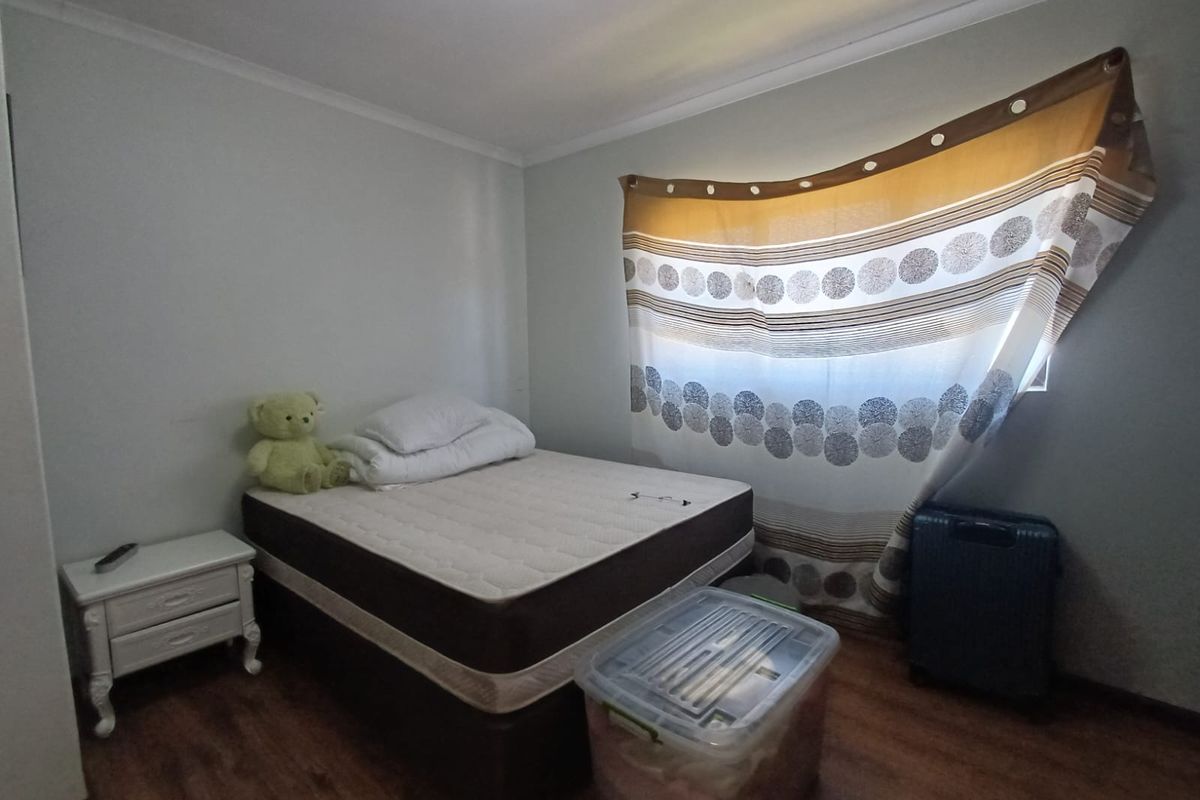 A bedroom featuring laminate flooring and a window with fitted curtain tracks.