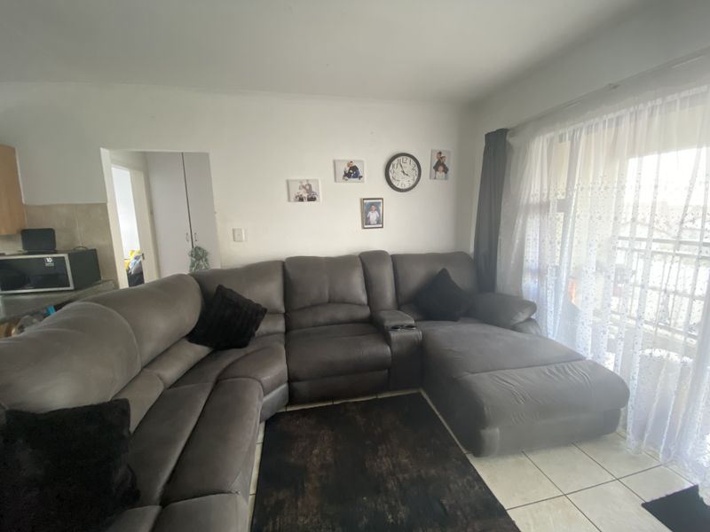 A living room area featuring tiled flooring and a sliding glass door providing natural light and access to the exterior.