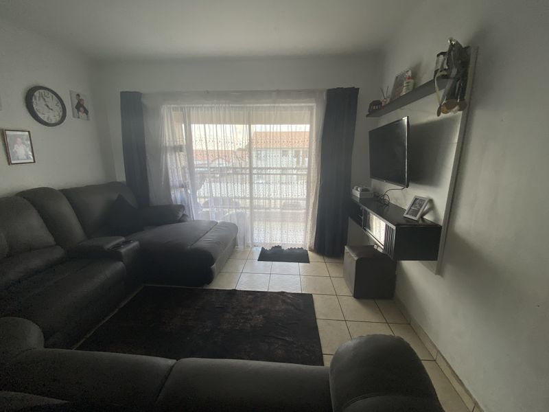 A living room featuring ceramic floor tiles and a sliding glass door providing natural light and access to the exterior.