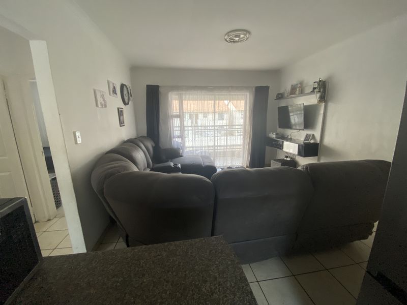 A living room area featuring tiled flooring, built-in shelving, and a sliding glass door leading to an outdoor space.