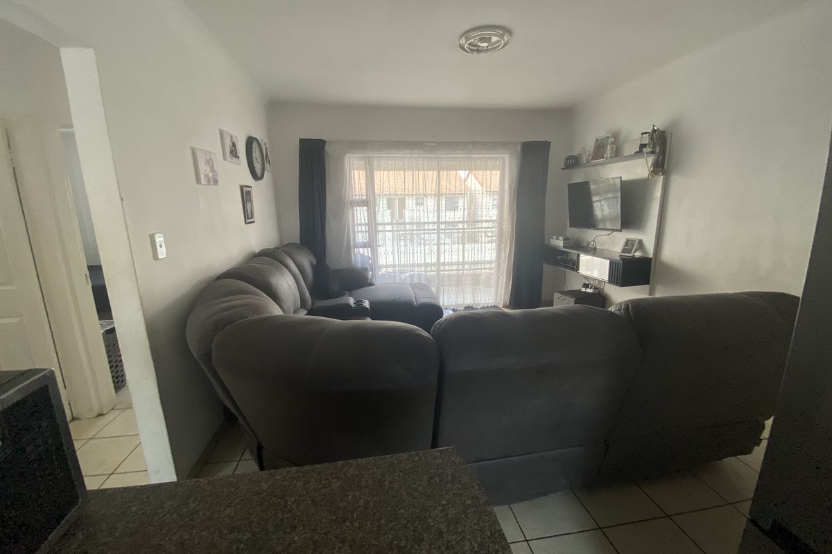 A living room area featuring tiled flooring, built-in shelving, and a sliding glass door leading to an outdoor space.