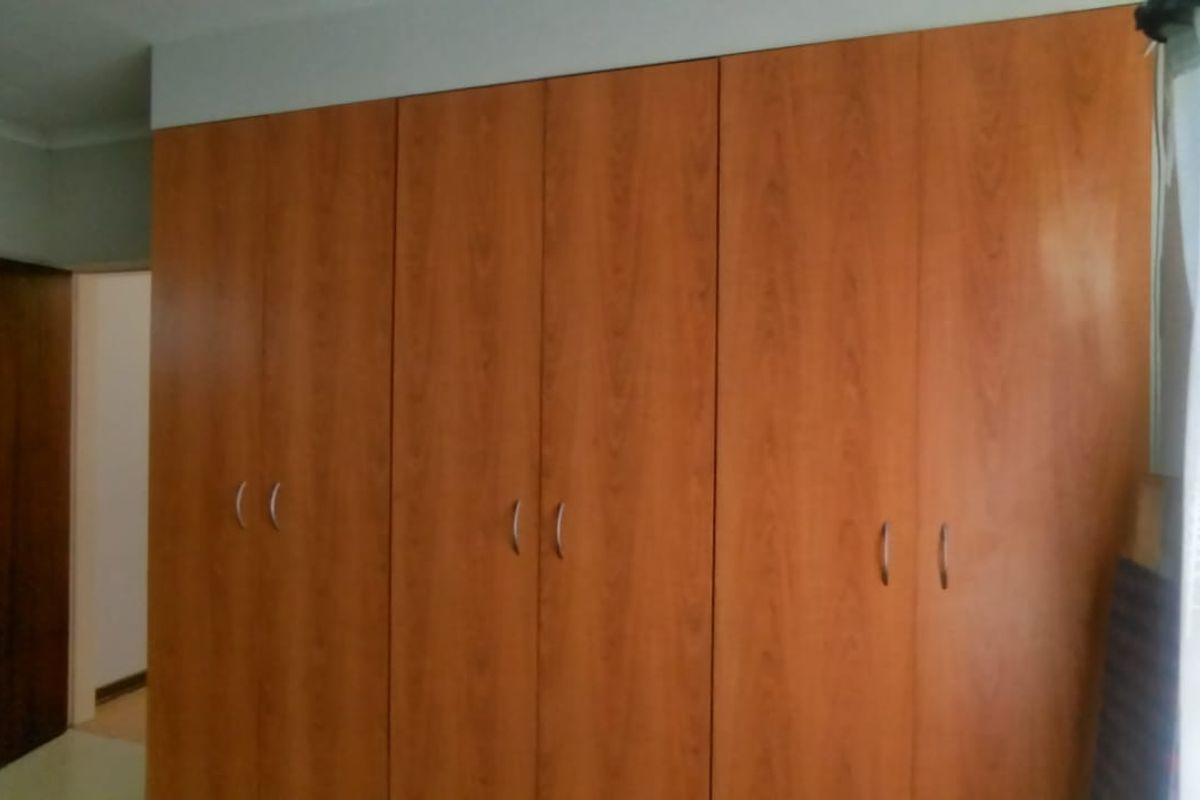 A bedroom featuring built-in wooden cupboards with a classic finish, providing ample storage space.