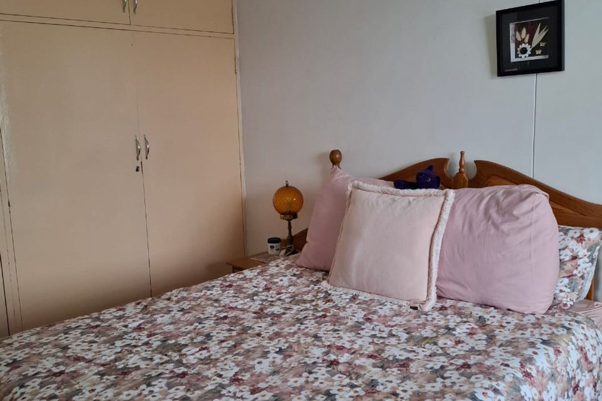 A bedroom featuring built-in cupboards and tiled flooring, providing a functional and practical living space.