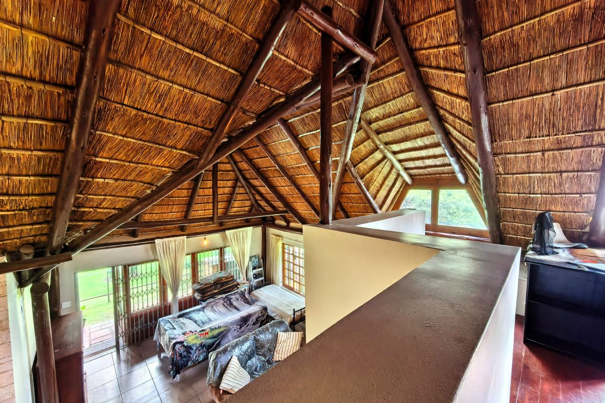 Spacious loft-style living area featuring a high vaulted thatched roof with exposed timber beams and tiled flooring.
