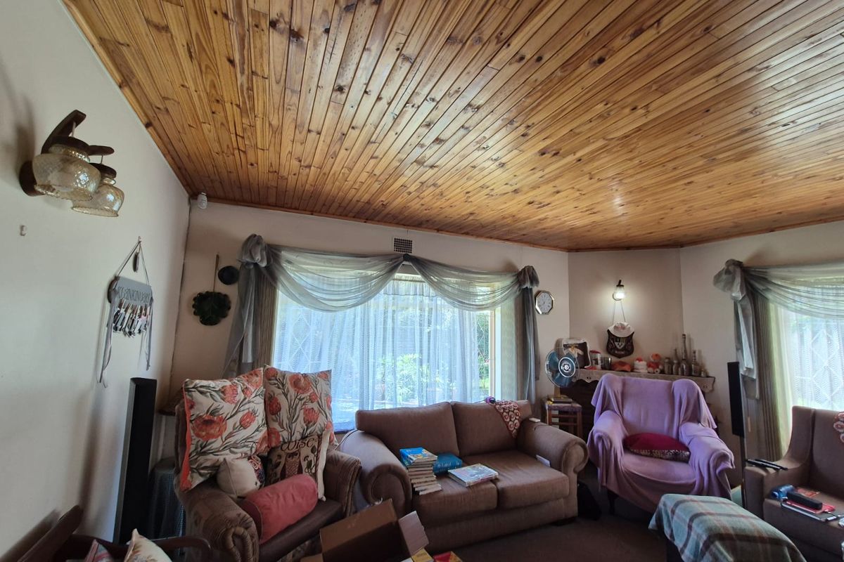 A spacious living room featuring a distinctive timber-clad ceiling and large windows that provide ample natural light.