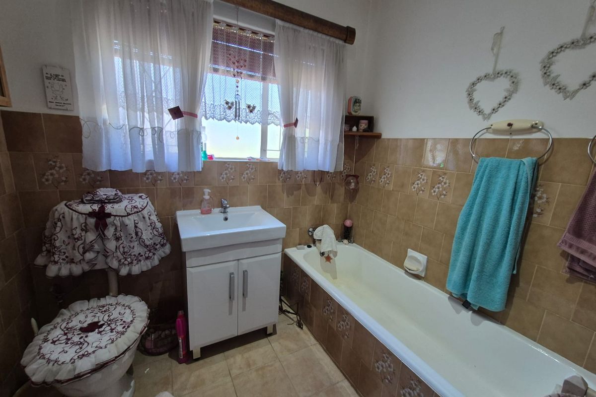 A functional bathroom featuring a built-in bathtub, vanity basin, and toilet, finished with traditional ceramic wall tiles.