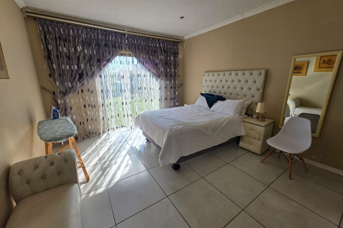 Spacious bedroom featuring large sliding glass doors with garden access, tiled flooring, and recessed ceiling lighting.