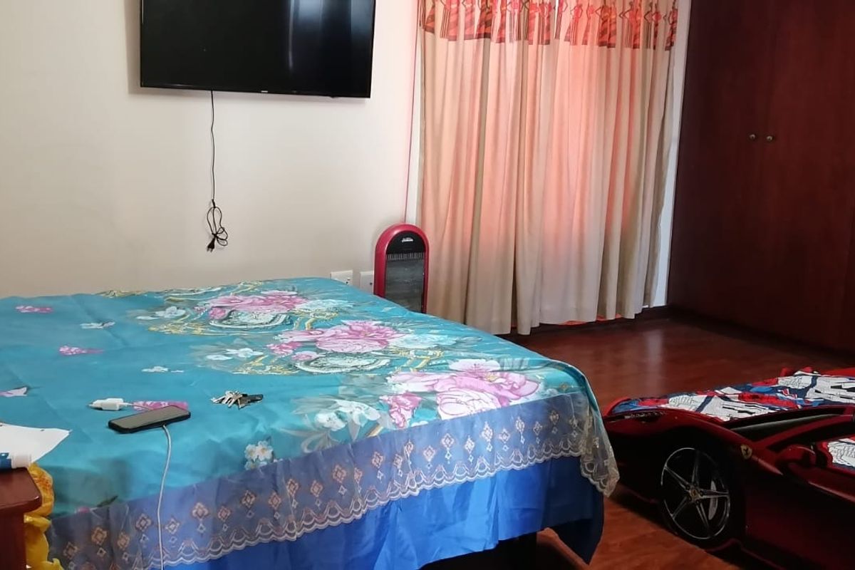 A bedroom featuring laminate flooring and built-in wooden cupboards, providing functional storage space within the room.