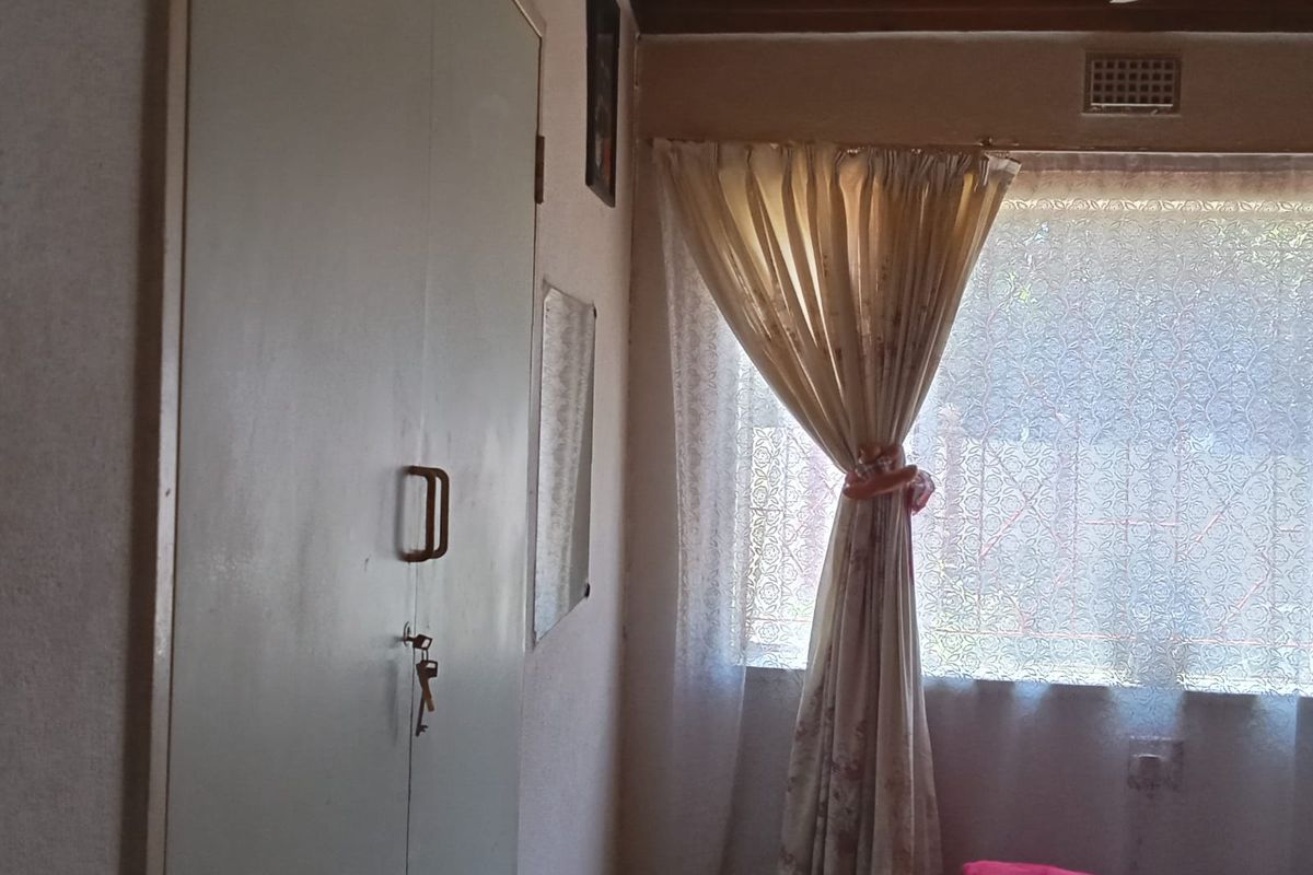 A bedroom featuring a built-in cupboard, timber-clad ceiling, and a window with natural light.