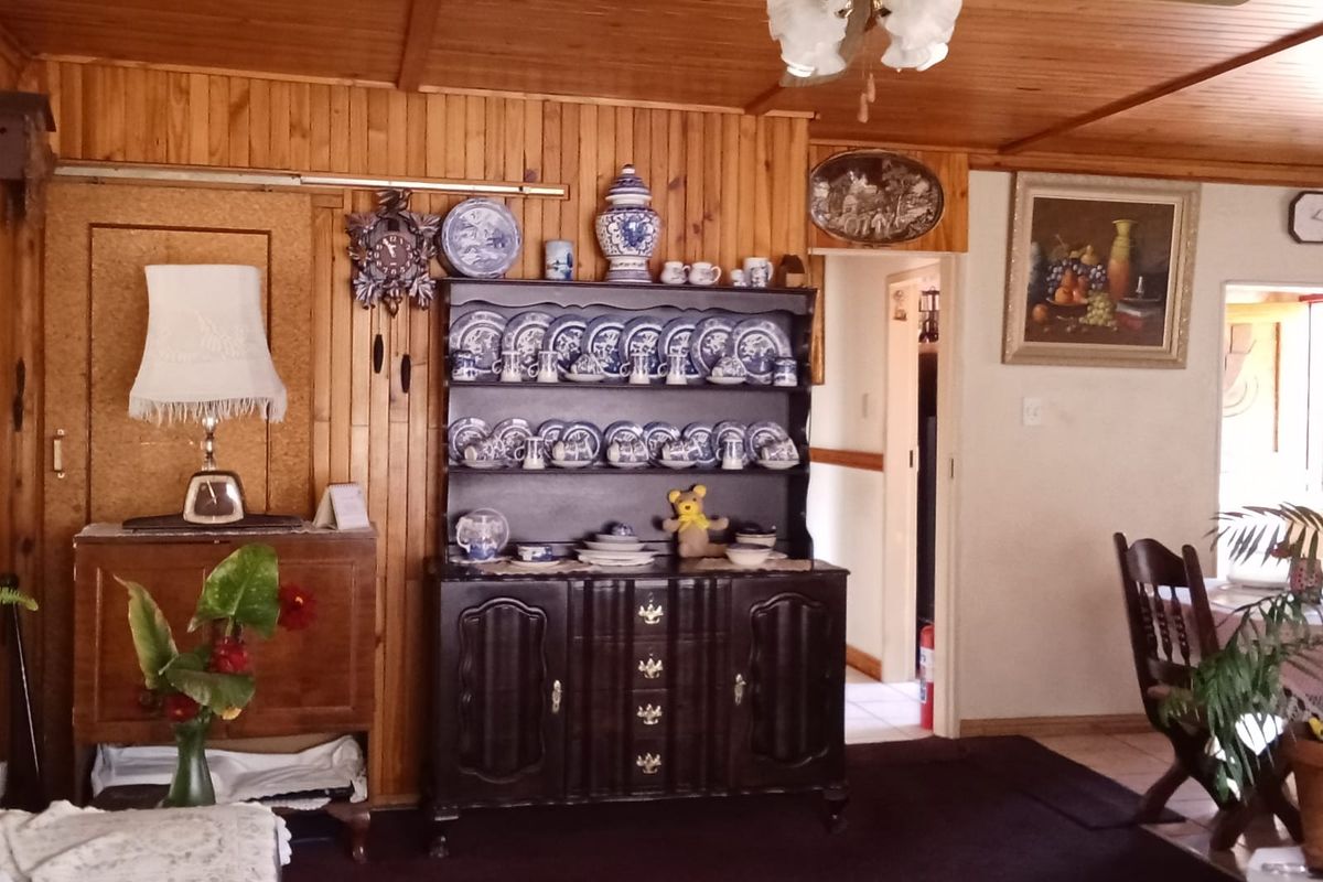 A living room featuring wood-paneled walls and ceiling, a ceiling fan, and dark carpeting, providing a traditional and cozy atmosphere.