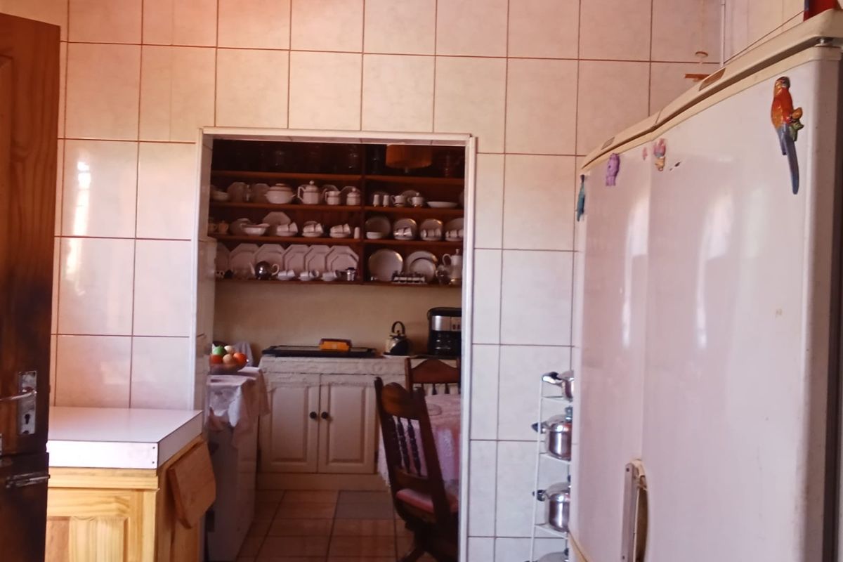 A view from the kitchen into a scullery area, featuring tiled walls, timber ceiling, and built-in cabinetry.