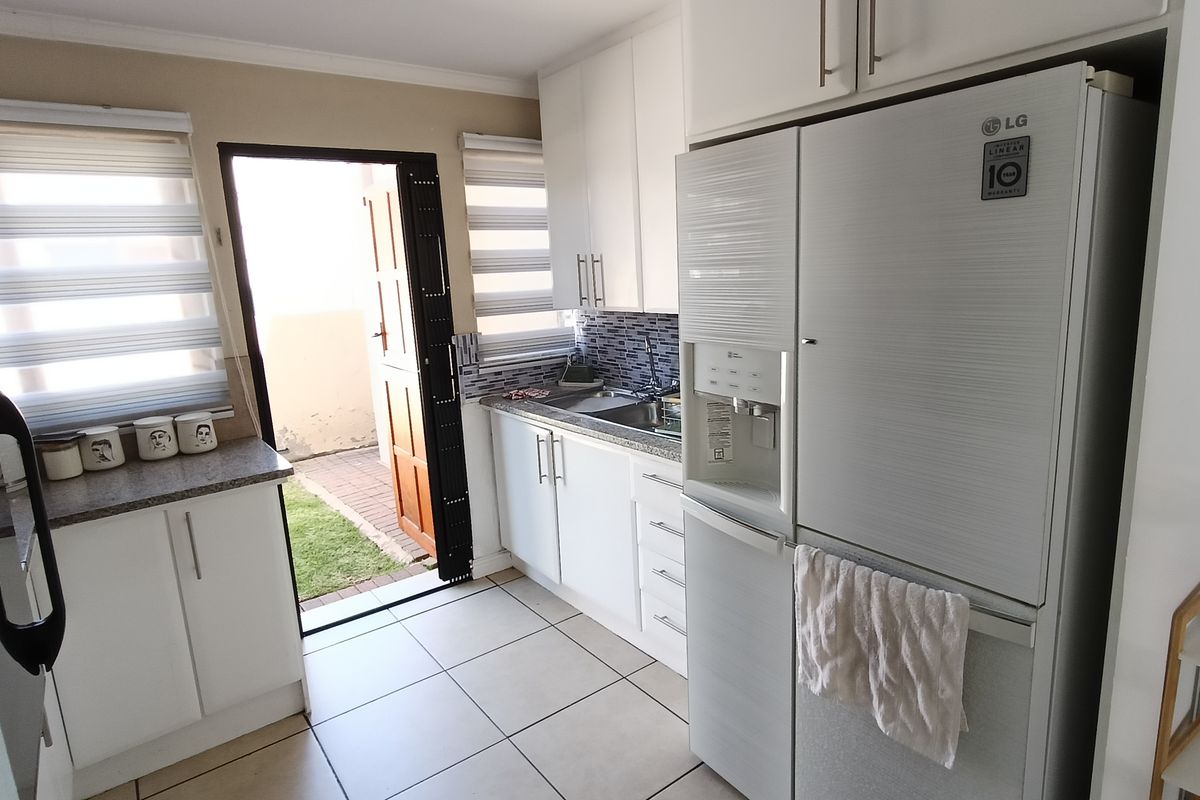 A functional kitchen featuring white cabinetry, tiled flooring, and direct access to an outdoor patio area.