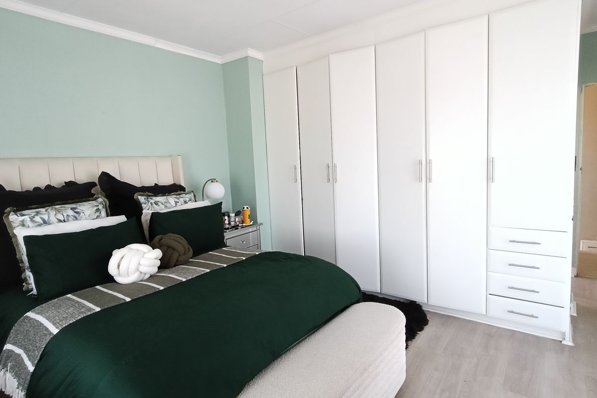 A well-maintained bedroom featuring extensive floor-to-ceiling built-in cabinetry with ample storage and light-toned laminate flooring.