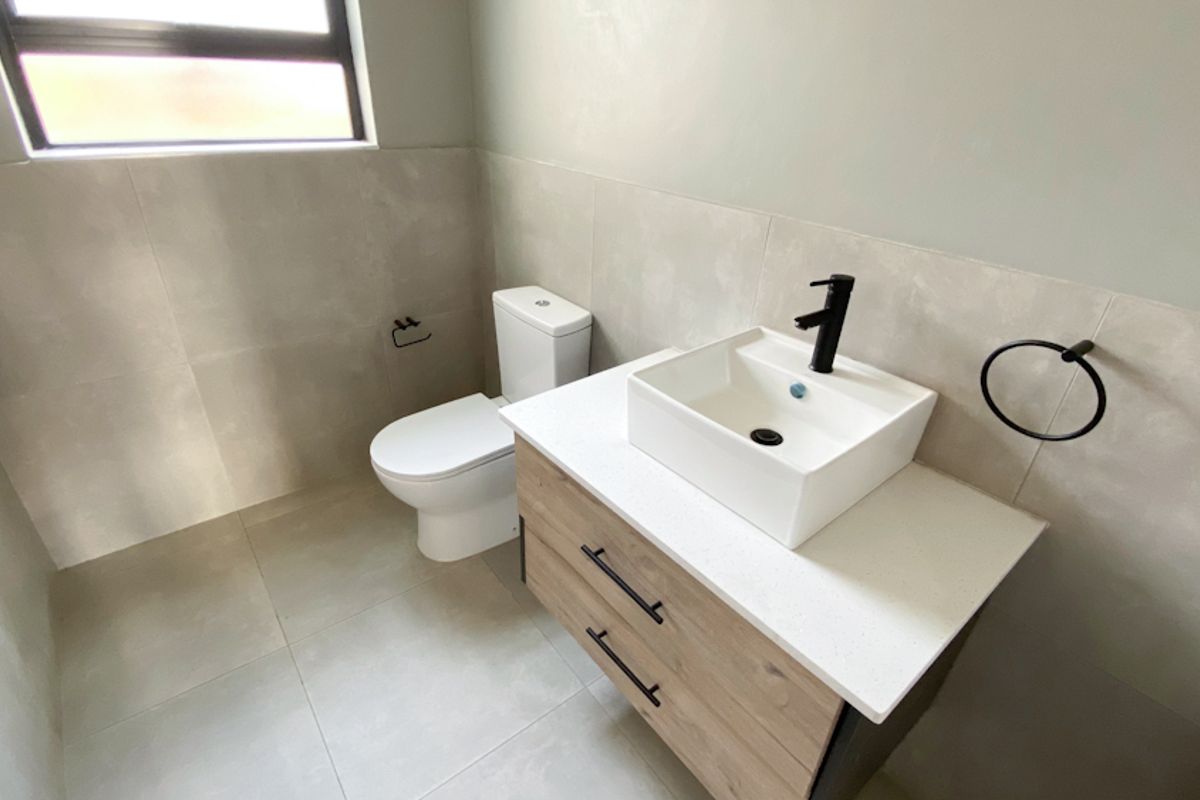 Modern bathroom featuring a contemporary vanity with a vessel sink, matte black fixtures, and neutral floor-to-ceiling wall tiles.