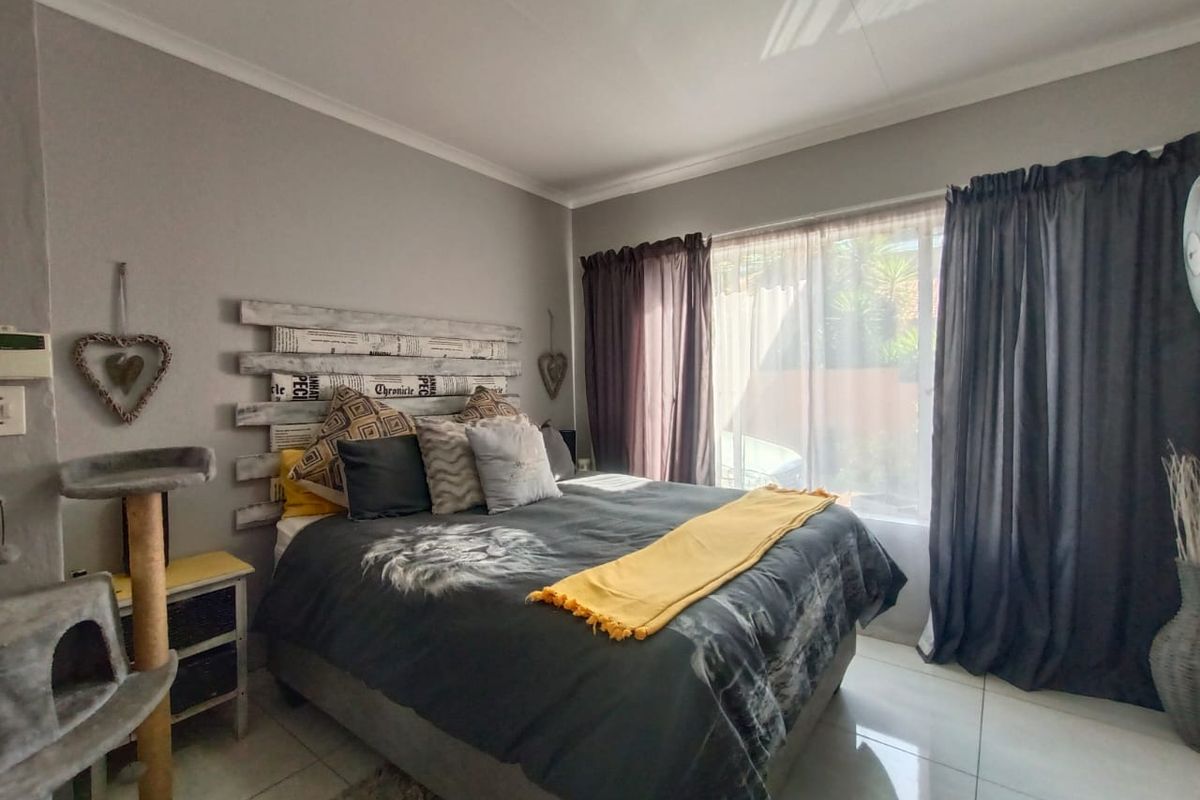 A well-lit bedroom featuring tiled flooring, neutral wall paint, and large windows with curtain tracks.