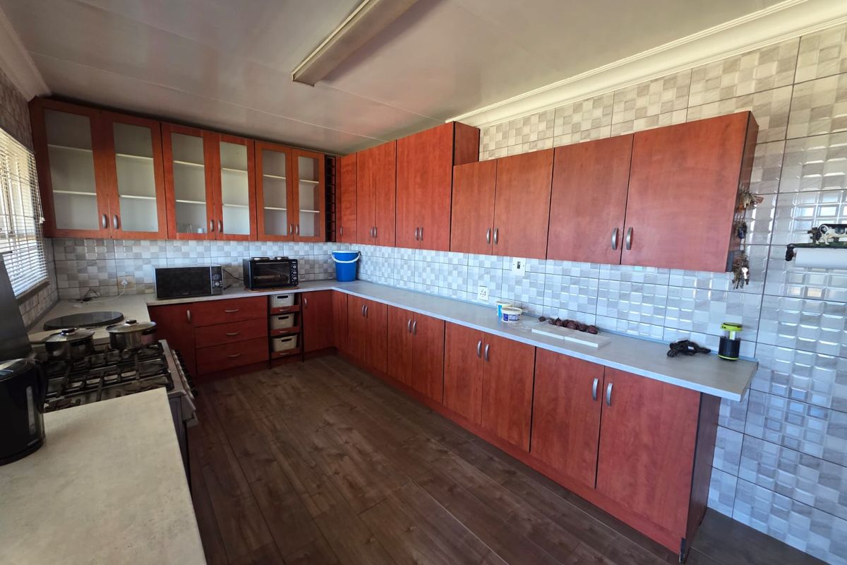 A functional kitchen featuring extensive wood-finish cabinetry, laminate countertops, and full-height wall tiling, providing ample storage and workspace.