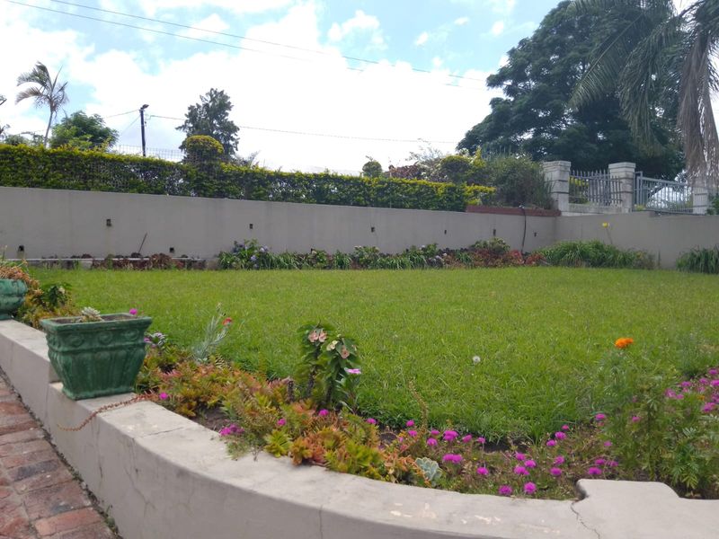A well-maintained garden featuring a manicured lawn, established flower beds, and a solid perimeter retaining wall.