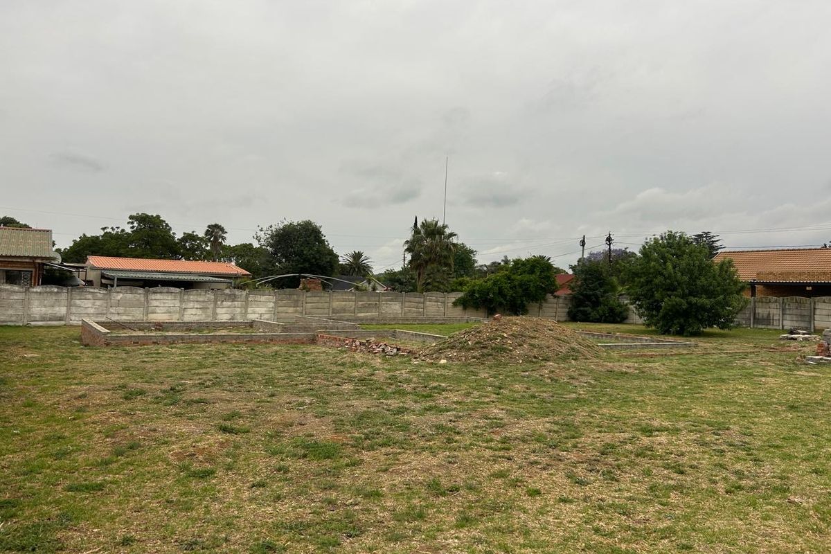 Vacant residential land featuring a grass lawn, perimeter precast concrete walling, and existing brick foundation footings ready for development.