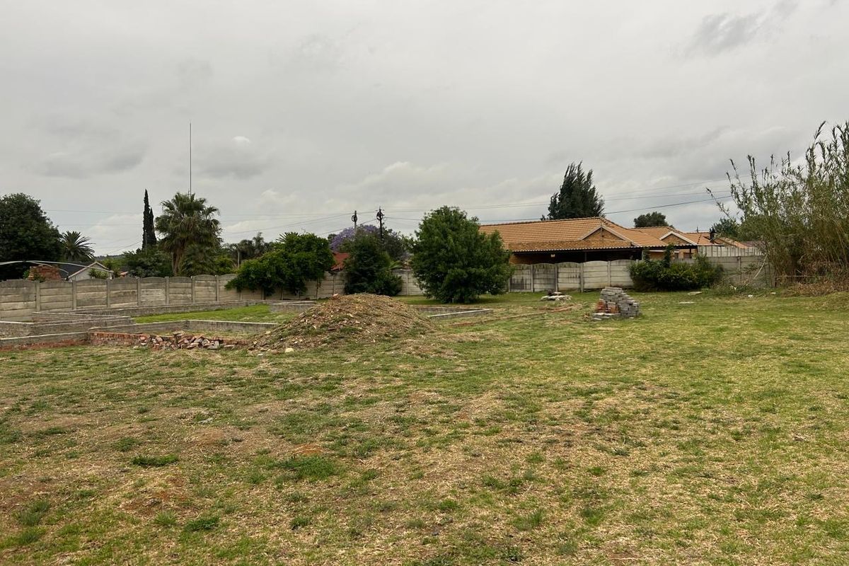 A vacant residential plot featuring a precast concrete boundary wall and an existing foundation slab, ready for development.