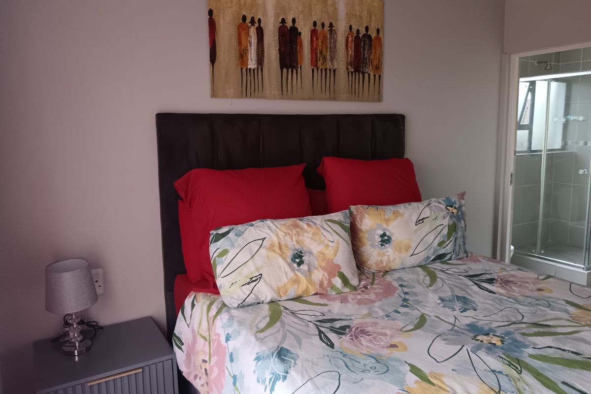 A bedroom featuring a neutral wall finish and an adjacent en-suite bathroom with a glass-enclosed shower.