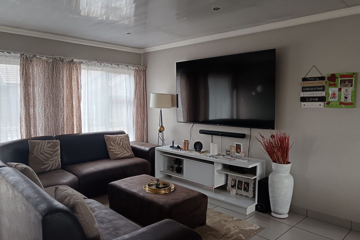 A comfortable living room featuring tiled flooring, recessed ceiling lighting, and a neutral color palette, providing a functional space for relaxation.