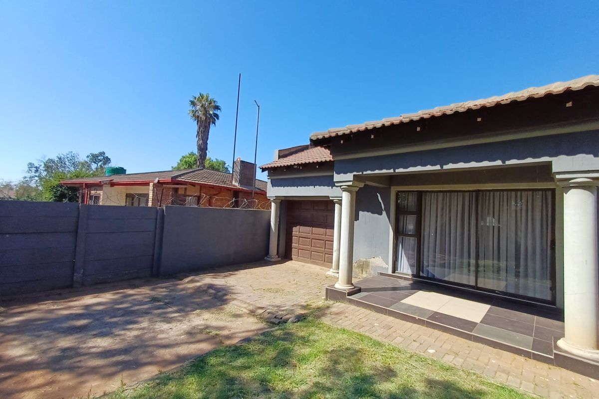 Exterior view of the property featuring a covered patio, paved driveway area, and a single garage with a tiled roof.