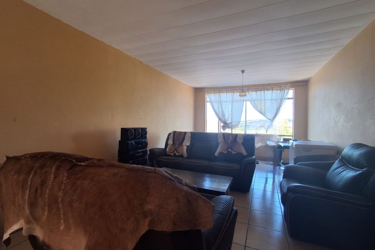 A spacious living room featuring tiled flooring and large windows that provide natural light and views.