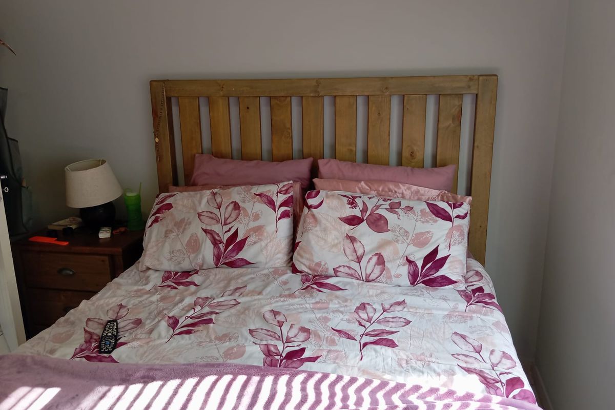 A bedroom featuring a wooden headboard and neutral wall finishes, providing a functional sleeping space.