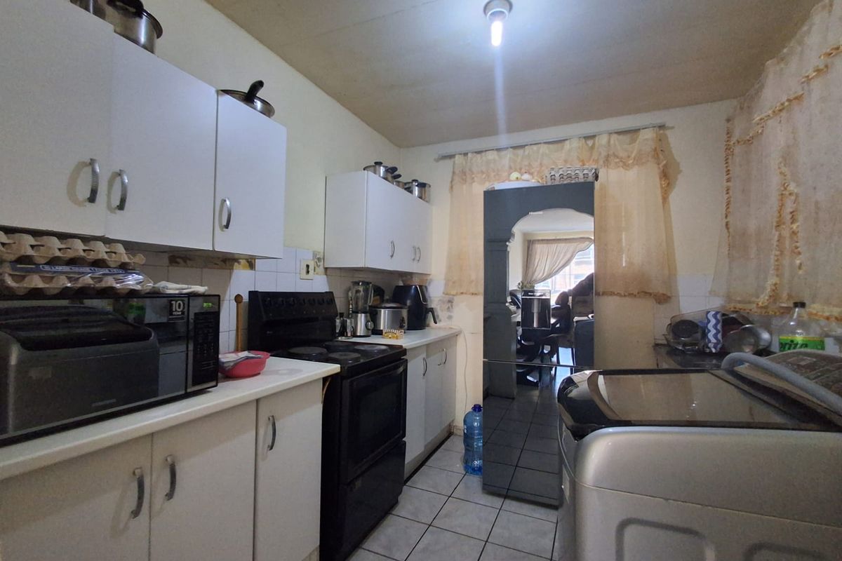 A functional kitchen featuring white cabinetry, tiled flooring, and a freestanding stove, offering a practical layout for daily meal preparation.