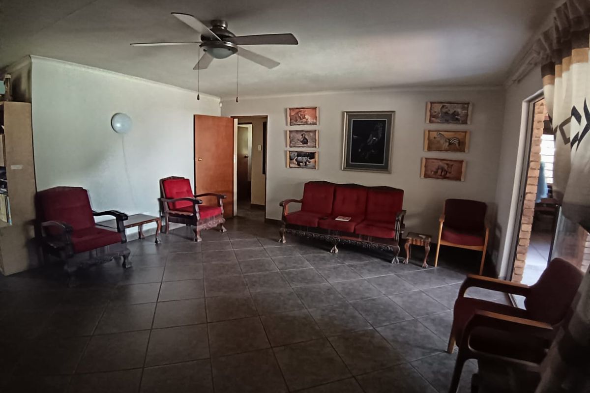Spacious living room featuring tiled flooring, a ceiling fan, and direct access to an adjacent area.