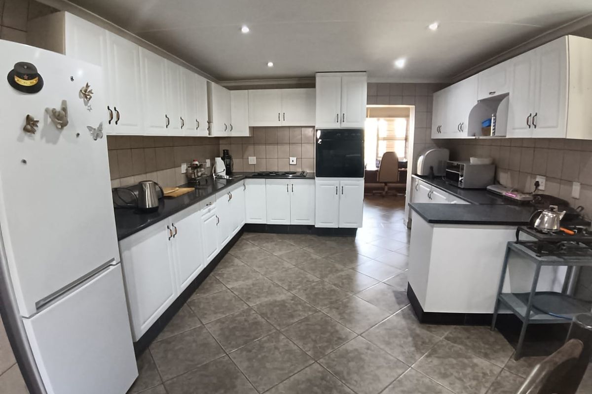 A functional kitchen featuring white cabinetry, dark countertops, tiled backsplash, and recessed lighting, offering a clean and practical workspace.