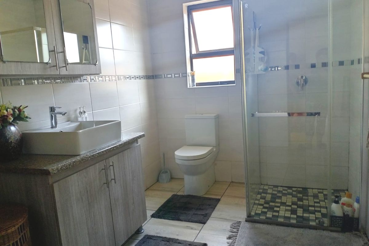 A modern bathroom featuring a glass-enclosed shower, a vanity with a vessel sink, and tiled walls and flooring.