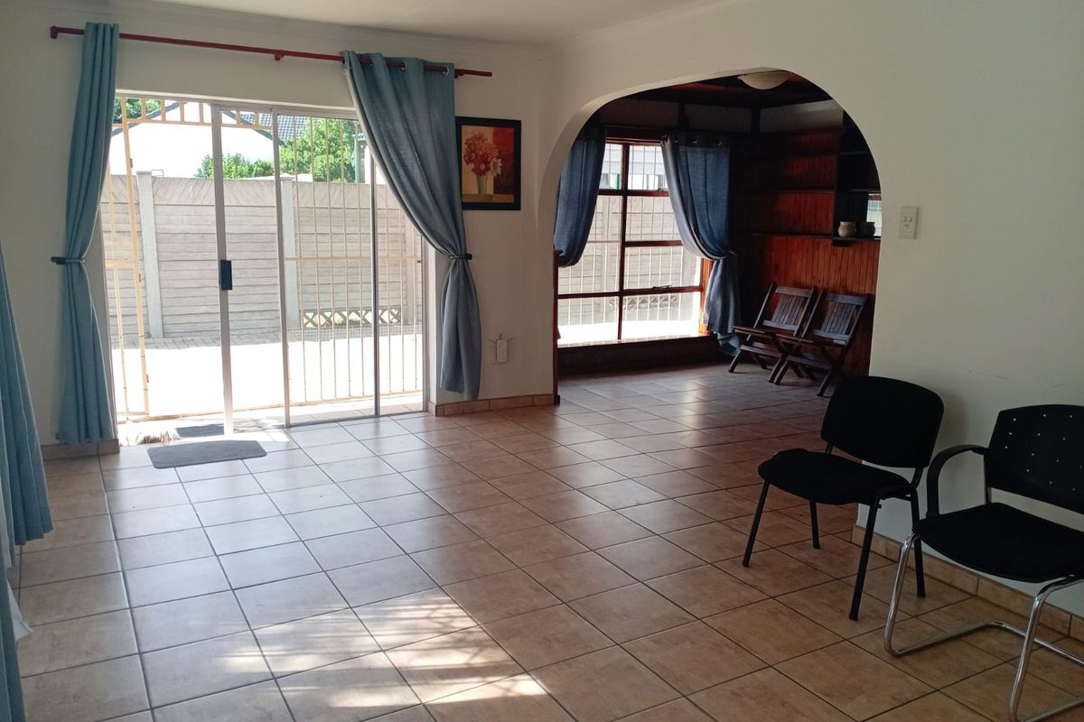 Spacious living area featuring ceramic floor tiles, an arched entryway to an adjacent room, and sliding glass doors providing access to the exterior.