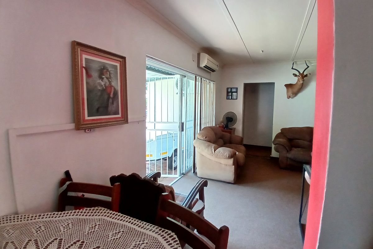 A living area featuring carpeted flooring, a wall-mounted air conditioning unit, and sliding glass doors leading to an outdoor space.