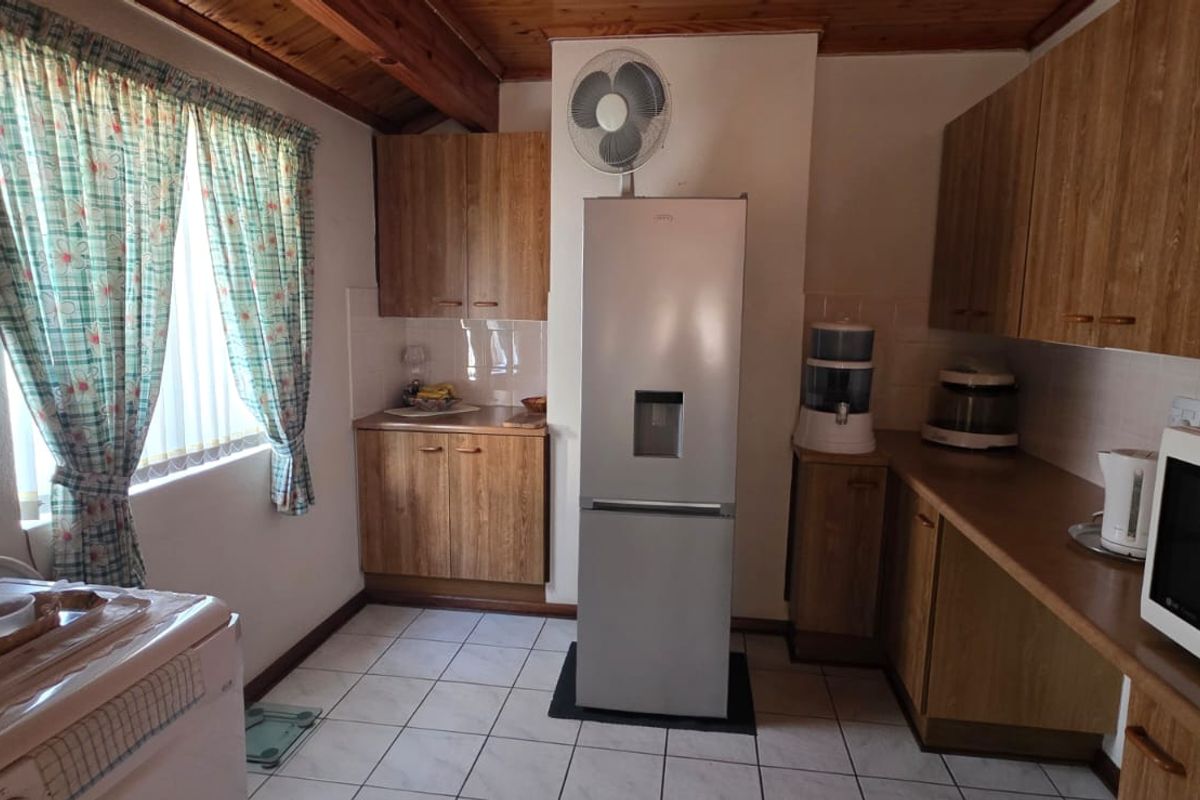 A functional kitchen featuring wood-look cabinetry, tiled flooring, and a timber-paneled ceiling, providing a practical workspace with ample storage.