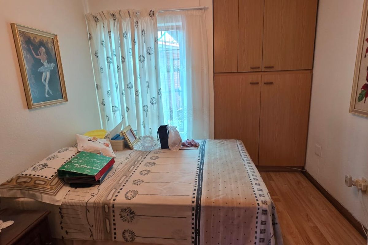 A compact bedroom featuring built-in wooden cabinetry and laminate flooring, providing functional storage and a neutral living space.