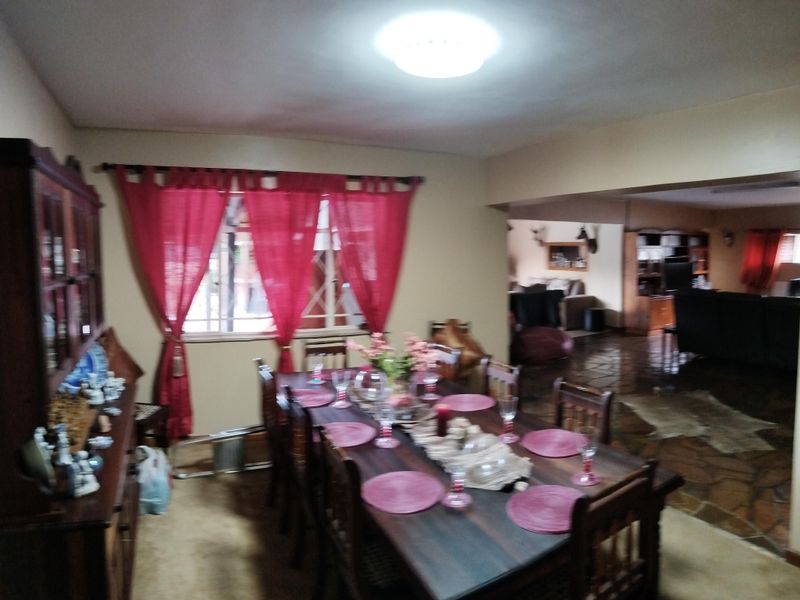 Open plan dining and living area featuring a combination of carpet and stone flooring with a central dining space.
