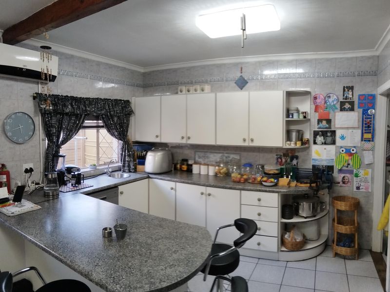 A functional kitchen featuring granite countertops, ample built-in cabinetry, tiled backsplash, and a breakfast bar area with tiled flooring.