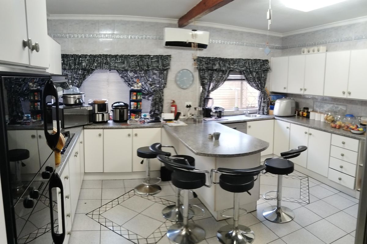 Spacious kitchen featuring a central island, ample built-in cabinetry, tiled flooring, and a split-system air conditioner for climate control.